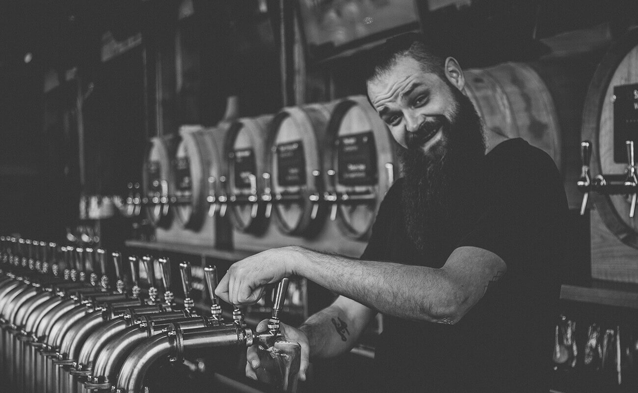 A person filling up cup with beer on tap
